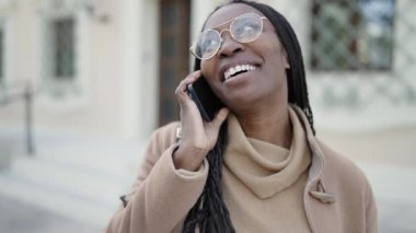 Sokakta gülümseyen Afrikalı kadın telefonda konuşuyor.