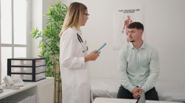 Genç çift doktor ve hasta dokunmatik ped kullanıyorlar klinikte tıbbi danışmanlık yapıyorlar.