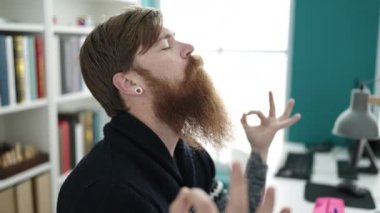 Genç kızıl saçlı erkek öğrenci kütüphane üniversitesinde yoga egzersizi yapıyor.