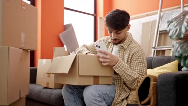 Jovem Árabe Homem Desembalagem Caixa Papelão Usando Smartphone Nova Casa — Vídeo de Stock
