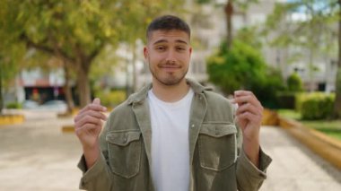 Kendinden emin gülümseyen genç İspanyol adam parktaki elleri kullanarak para harcıyor.