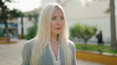 Young blonde woman executive smiling confident standing at park