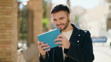 Young hispanic man smiling confident playing video game at street