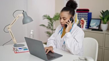 Genç Afrikalı Amerikalı kadın doktor klinikte bilgisayarla konuşuyor.