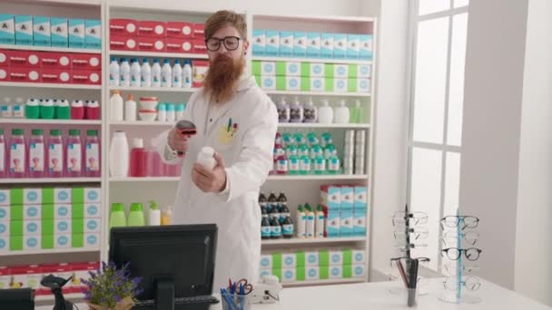Νεαρή Κοκκινομάλλα Φαρμακοποιός Σάρωση Μπουκάλι Χάπια Χρησιμοποιώντας Υπολογιστή Στο Φαρμακείο — Αρχείο Βίντεο