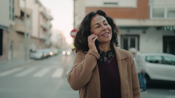中世のヒスパニック女性笑顔自信を持って話す上のスマートフォンでストリート — ストック動画