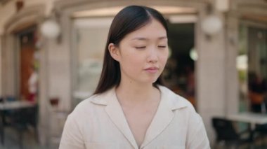 Sokakta kendinden emin gülümseyen Çinli kadın.