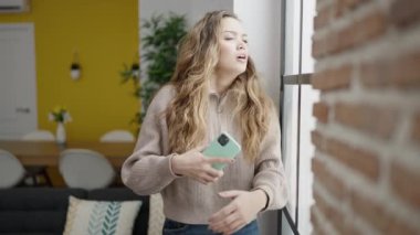 Genç, güzel, İspanyol bir kadın evde akıllı telefon kullanıyor.