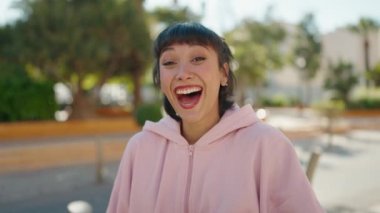 Genç İspanyol kadın gülümsüyor. Sokakta kendinden emin konuşuyor.