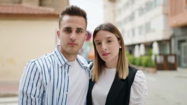 Kadın ve erkek gülümsüyor. Kendilerine güveniyorlar. Sokakta sarılıyorlar.