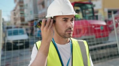 Genç İspanyol mimar sokakta akıllı telefondan sesli mesaj dinliyor.