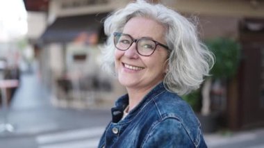 Middle age woman with grey hair smiling confident at street