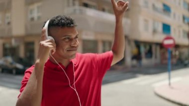 Young latin man smiling confident listening to music at street