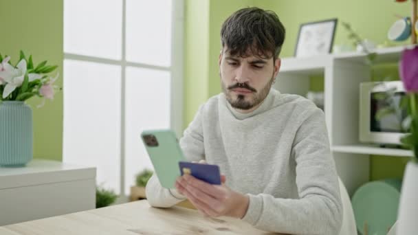 Молодий Іспаномовний Чоловік Купує Онлайн Смартфоном Сидячи Столі Їдальні — стокове відео