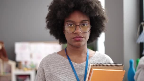 Afroamerikanische Kindergärtnerin Lächelt Selbstbewusst Und Hält Bücher Kindergarten — Stockvideo
