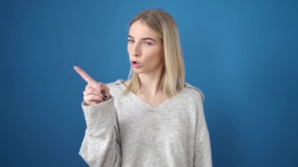 Молода Блондинка Стоїть Серйозним Виразом Вказуючи Пальцем Ізольований Синій Фон — стокове відео