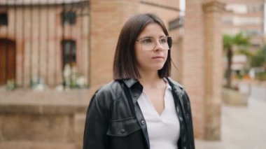 Young hispanic woman standing with serious expression at street