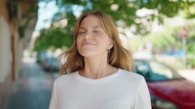 Young blonde girl smiling confident standing at street