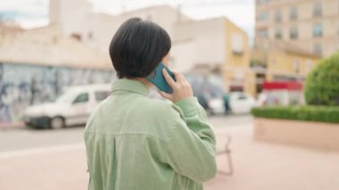 Sokakta yürürken akıllı telefondan konuşan genç Çinli kadın.