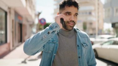Genç Arap adam gülümsüyor, kendinden emin bir şekilde caddedeki akıllı telefondan konuşuyor.