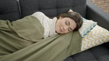 Young beautiful hispanic woman lying on sofa sleeping at home