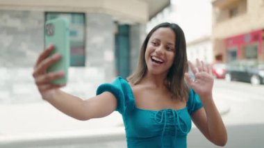 Young hispanic woman smiling confident having video call at street