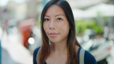 Kahvecinin terasında kendine güvenen Asyalı genç kadın gülümsüyor.