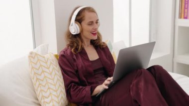 Young beautiful hispanic woman having video call sitting on bed at bedroom