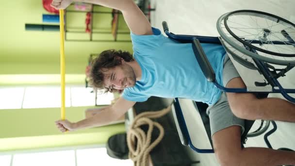 Young Hispanic Man Sitting Wheelchair Stretching Arms Elastic Band Rehab — Stock video