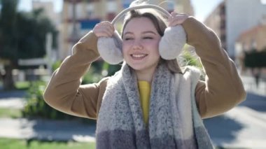 Sokakta kendine güvenen, kulaklık ve eşarp takan genç sarışın kadın.