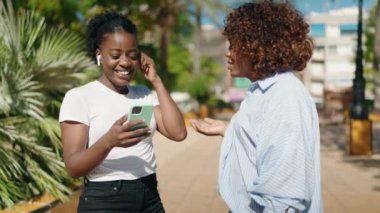 African american women mother and daughter listening to music and dancing at park