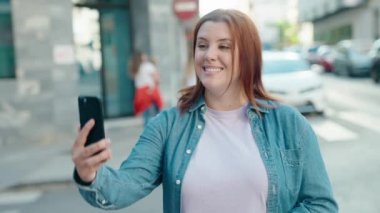 Young beautiful plus size woman smiling confident having video call at street
