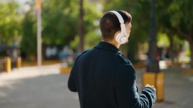 Young hispanic man smiling confident listening to music at park