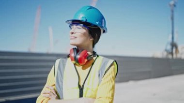 Güzel İspanyol kadın mimar gülümsüyor. Kollarını kavuşturup caddede duruyor.