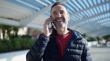 Middle age man smiling confident talking on smartphone at park