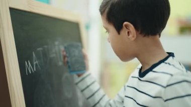 Sevimli İspanyol çocuk anaokulu öğrencisi sınıftaki tahtayı siliyor.