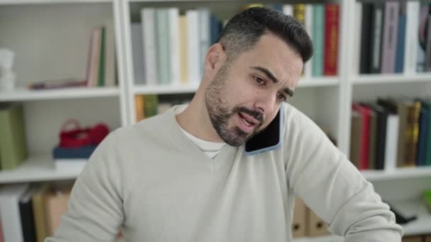 Young Hispanic Man Student Using Computer Talking Smartphone Library University — Stock videók
