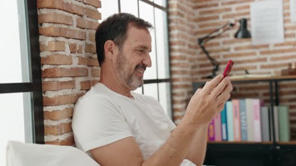 Medelålders Man Med Smartphone Sitter Sängen Sovrummet — Stockvideo