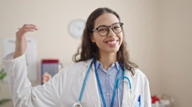 Genç, güzel İspanyol kadın doktor gülümsüyor. Kendine güveniyor. Klinikte iyi bir jest yapıyor.
