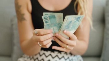 Genç bir kadın Brezilya 'da 100 banknot sayıyor.