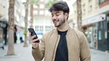 Genç İspanyol adam akıllı telefon kullanıyor. Sokakta kazanan yüz ifadesi var.