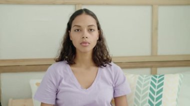 Young african american woman smiling confident sitting on bed at bedroom