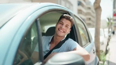 Young hispanic man smiling confident holding key of new car at street