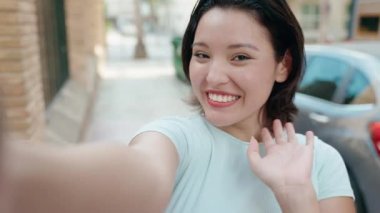 Young hispanic woman smiling confident having video call at street