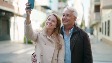 Middle age couple couple smiling confident making selfie by the smartphone at street