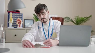 Genç İspanyol doktor klinikteki panoda dizüstü bilgisayar kullanıyor.
