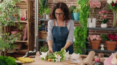 Çiçekçide elinde buket çiçek tutan orta yaşlı bir kadın.