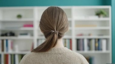 Young blonde woman student smiling confident standing at library university