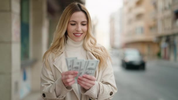 年轻的金发女人满脸笑容 自信地在街上数钱 — 图库视频影像