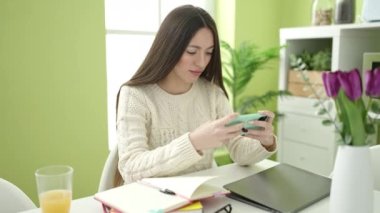 Genç, güzel İspanyol kız öğrenci akıllı telefonuyla evde oyun oynuyor.